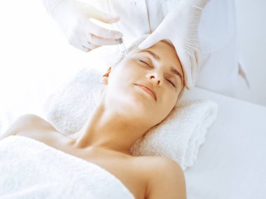 Güzellik uzmanı elleri klinikte şırıngalı kadın sarışına güzellik prosedürü uyguluyor. Kozmetik tıp ve cerrahi, güzellik enjeksiyonları konsepti