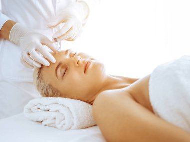 Güzellik uzmanı elleri klinikte şırıngalı kadın sarışına güzellik prosedürü uyguluyor. Kozmetik tıp ve cerrahi, güzellik enjeksiyonları konsepti