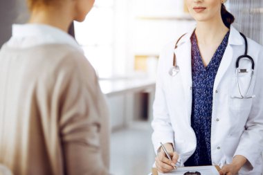 Doktor ve hasta güneşli klinikte otururken sağlık muayenesini tartışıyorlar. Tıp konsepti