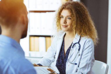 Kadın doktor ve erkek hasta güneşli klinikte otururken sağlık muayenesini tartışıyorlar. Tıp konsepti