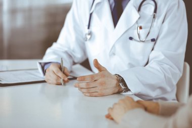 Bilinmeyen erkek doktor ve hasta kadın klinikte oturup dosya kullanırken bir şey tartışıyorlar. Hastanedeki en iyi sağlık hizmeti, ilaç, salgın durdurma.