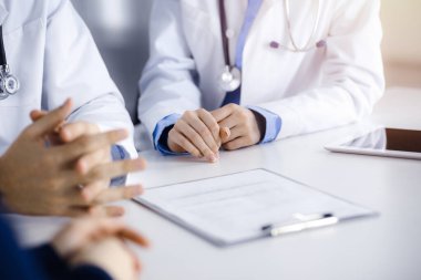 Bilinmeyen bir grup doktor masanın başında oturmuş güneşli hastane ofisinde hastalıkların tedavisini tartışıyorlar. Covid 2019