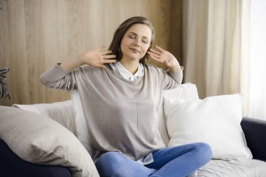 Mutlu esmer kadın ellerini başının arkasına koyuyor koltuğa yaslanıyor Avrupalı kadın tembel hafta sonunun keyfini çıkarıyor ya da sıcak oturma odasında tatilin tadını çıkarıyor, ev hanımı ev işi yaptıktan sonra rahatlıyor.