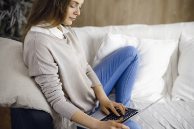 İş kadını, Covid-19 karantinası sırasında rahat oturma odasında dizüstü bilgisayarda çalışıyor. Coronavirus salgını sırasında evde konsept kal