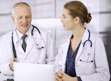 Yaşlı doktor ve bayan meslektaşı klinikte çalışırken güncel hastalık terapisini tartışıyorlar. Hastanede takım çalışması. Tıp ve sağlık hizmetleri kavramı