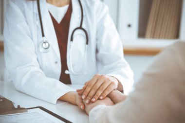 Kadın hastasına güvence veren kimliği belirsiz kadın doktorun elleri, yakın plan. Tıp konsepti