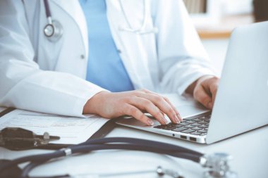 Masada otururken dizüstü bilgisayarda yazan kimliği belirsiz kadın doktor. Tıp konsepti