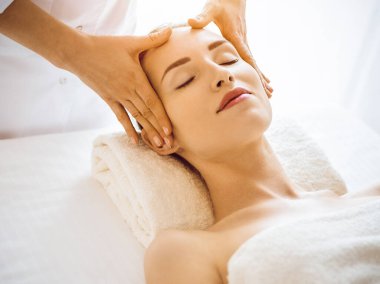 Güneşli kaplıcalarda yüz masajından hoşlanan güzel bir kadın.