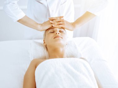 Güzeller güzeli sarışın kadın spa merkezinde yüz masajından hoşlanıyor. Tıp ve güzellik kavramlarında rahatlatıcı tedavi