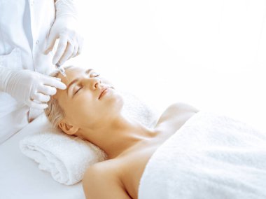 Güzellik uzmanı elleri klinikte şırıngalı kadın sarışına güzellik prosedürü uyguluyor. Kozmetik tıp ve cerrahi, güzellik enjeksiyonları konsepti