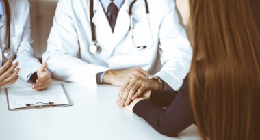 Bilinmeyen erkek-doktor, kadın hastasına güvence veriyor, yakın plan. İki doktor kadınlara danışmanlık yapıyor ve tavsiyelerde bulunuyor. Mükemmel tıbbi hizmet, Coronavirus salgını sırasında tıpta empati. Kapalı