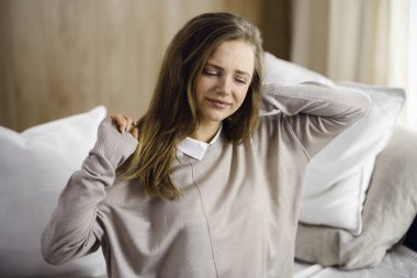 Yorgun bir kadın masaj yapıyor, boynu ağrıyor, kasları geriliyor bilgisayar çalışmalarından dolayı yorgun düşmüş. Coronavirus salgını ve kendini izolasyon karantinası süresince evde kal