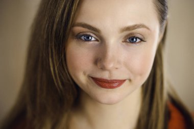 Zeki, kendinden emin, gülümseyen, Avrupalı bir kadının kollarını kavuşturup evinde dikilirken çekilmiş bir fotoğrafı. Çekici genç kız öğrenci serbest çalışan, kırmızı giyinmiş, kameraya bakıyor.