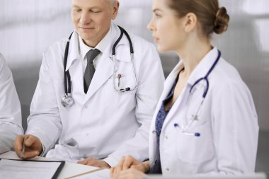 Doktor meslektaşları ve yaşlı terapist klinikte çalışırken güncel hastalık terapisini tartışıyorlar. Hastanede takım çalışması. Tıp ve sağlık hizmetleri kavramı