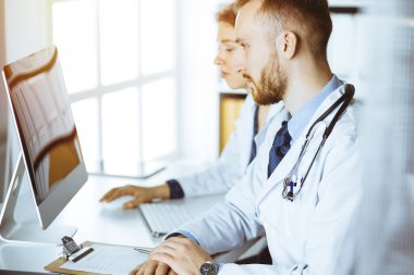 Kızıl sakallı doktor ve bayan meslektaşı güncel hastalık terapisini güneşli klinikte çalışırken tartışıyorlar. Tıpta takım çalışması