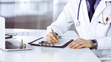 Bilinmeyen erkek doktor, klinikteki ilaç geçmişi kayıtlarıyla birlikte yakın planda oturuyor. İşteki genç doktor. Mükemmel sağlık hizmeti, tıp konsepti