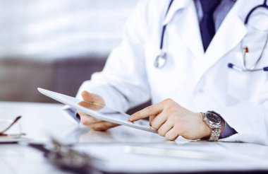 Bilinmeyen erkek doktor klinikteki tablet bilgisayarla yakın planda çalışıyor. İşteki genç doktor. Mükemmel sağlık hizmeti, tıp konsepti