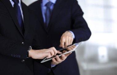 İş adamları yeni projelerini tartışmak için bir tablet bilgisayar kullanıyorlar, modern bir ofiste duruyorlar. İş yerinde iş arkadaşı olan tanınmamış bir iş adamı ya da erkek girişimci. Takım çalışması ve ortaklık