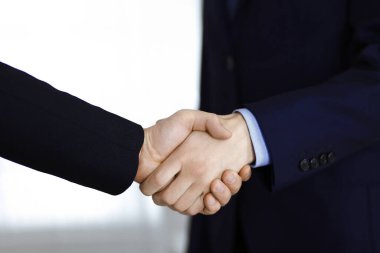 İş adamları el sıkışıyor, yakın plan. Modern bir ofiste duran bir grup tanınmamış iş adamı. Takım çalışması, ortaklık ve el sıkışma kavramı