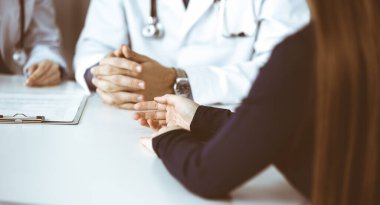 Meçhul erkek doktor modern klinikte otururken hasta kadını dinliyor. Mükemmel tıbbi servis, Coronavirus salgını sırasında ilaç konsepti. Covid 2019