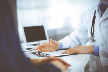 Bir doktor, hastanedeki dolapta birlikte otururken hastasıyla konuşuyor. Doktor ilaç kayıtlarını doldurmak için pano kullanıyor. Mükemmel tıbbi hizmet...