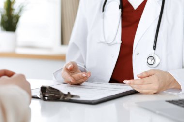 Bilinmeyen kadın doktor ve hasta klinikteki masada otururken bir şey tartışıyorlar, yakın plan. Tıp konsepti