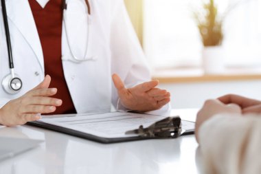 Bilinmeyen kadın doktor ve hasta güneşli klinikteki masada otururken bir şey tartışıyorlar.