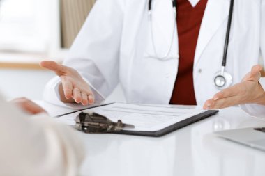 Bilinmeyen kadın doktor ve hasta klinikteki masada otururken bir şey tartışıyorlar, yakın plan. Tıp konsepti