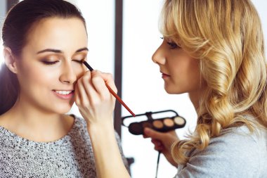 Profesyonel makyöz güzel genç bir kadınla çalışıyor. Gelin, moda ya da çıplak stil