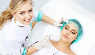 Kadın yüzüne kaş dövmesi yapan profesyonel bir güzellik uzmanı. Güzellik salonunda kalıcı kaş makyajı, yakın çekim. Kozmetoloji tedavisi