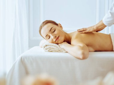 Güzel bir kadın kapalı gözlerle sırt masajından hoşlanıyor. Spa tedavisi kavramı