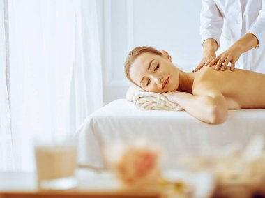 Güzel bir kadın kapalı gözlerle sırt masajından hoşlanıyor. Spa tedavisi kavramı