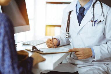 Bilinmeyen sakallı doktor ve hasta kadın güneşli klinikte otururken sağlık muayenesini tartışıyorlar.