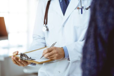 Bilinmeyen sakallı doktor ve hasta kadın güneşli klinikte otururken sağlık muayenesini tartışıyorlar.