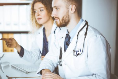 Kızıl sakallı doktor ve bayan meslektaşı güncel hastalık terapisini güneşli klinikte çalışırken tartışıyorlar. Tıpta takım çalışması