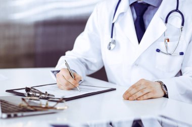 Bilinmeyen erkek doktor, klinikteki ilaç geçmişi kayıtlarıyla birlikte yakın planda oturuyor. İşteki genç doktor. Mükemmel sağlık hizmeti, tıp konsepti