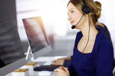 İki iş kadını, güneşli bir modern ofiste masada otururken, müşterilerle kulaklıkla sohbet ediyorlar. Çağrı merkezinde çeşitli insanlar. Tele pazarlama ve müşteri hizmetleri