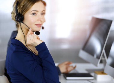 İki iş kadını, güneşli bir modern ofiste masada otururken, müşterilerle kulaklıkla sohbet ediyorlar. Çağrı merkezinde çeşitli insanlar. Tele pazarlama ve müşteri hizmetleri