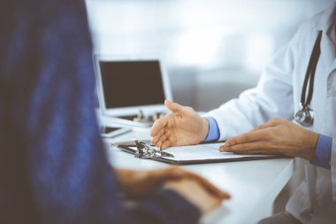 Bir doktor, hastanedeki dolapta birlikte otururken hastasıyla konuşuyor. Doktor ilaç kayıtlarını doldurmak için pano kullanıyor. Mükemmel tıbbi hizmet...