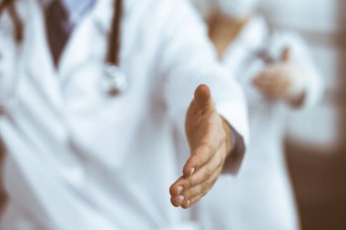 Bilinmeyen erkek doktor ve kadın takım olarak ayakta duruyor ve modern klinikte yardım eli uzatıyorlar. Mükemmel bir tıbbi hizmet, Coronavirus salgını sırasında ilaç. Covid 2019