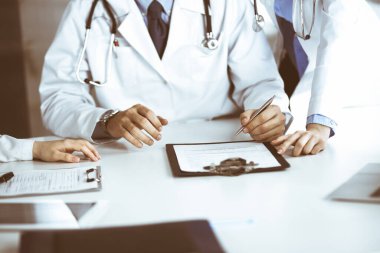 Bilinmeyen bir grup doktor masanın başında oturmuş modern hastane ofisindeki hastalıkları veya hastalıkları tartışıyorlar. Coronavirus dengeleyici, ilaç konseptinde hasta yardımı