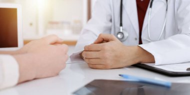 Bilinmeyen kadın doktor ve hasta güneşli klinikteki masada otururken bir şey tartışıyorlar.