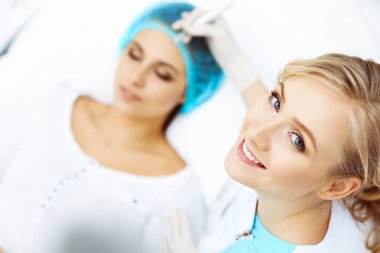 Kadın yüzüne kaş dövmesi yapan profesyonel bir güzellik uzmanı. Güzellik salonunda kalıcı kaş makyajı, yakın çekim. Kozmetoloji tedavisi