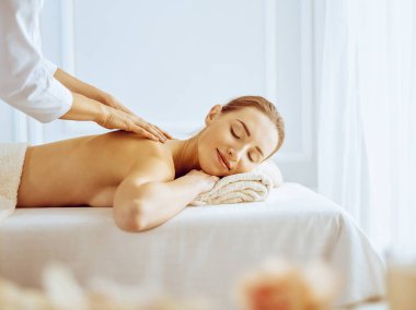 Güzel bir kadın kapalı gözlerle sırt masajından hoşlanıyor. Spa tedavisi kavramı