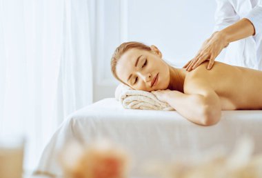 Güzel bir kadın kapalı gözlerle sırt masajından hoşlanıyor. Spa tedavisi kavramı