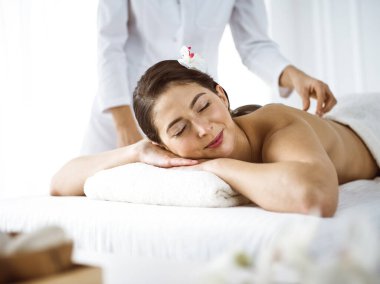 Güzel esmer kadın rahat ve mutlu bir şekilde sırt masajı yapıyor. Spa ve tıp konsepti