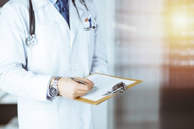 Bilinmeyen erkek doktor, çalıştığı yerdeki güneşli klinikte panoya yazı yazıyor.