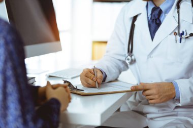 Bilinmeyen sakallı doktor ve hasta kadın güneşli klinikte otururken sağlık muayenesini tartışıyorlar.