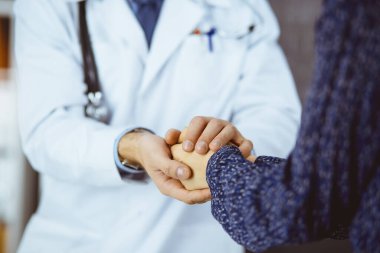 Dost canlısı erkek doktor, güneşli klinikte kadın hastasına güven veriyor. Tıp etiği ve güven kavramı, tıp teması