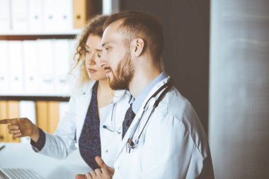 Kızıl sakallı doktor ve bayan meslektaşı güncel hastalık terapisini güneşli klinikte çalışırken tartışıyorlar. Tıpta takım çalışması